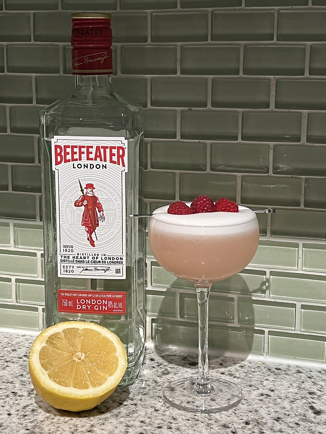 A clover club cocktail next to a bottle of Beefeater gin